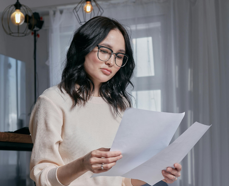 Woman reviewing financial documents thoughtfully, symbolizing debt management strategies.